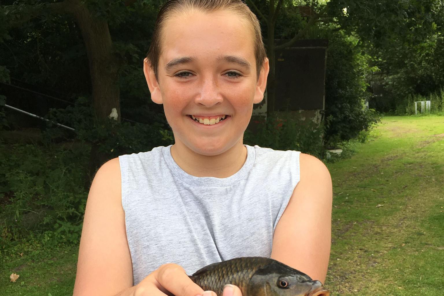 Charlie as a child smiling and holding a fish