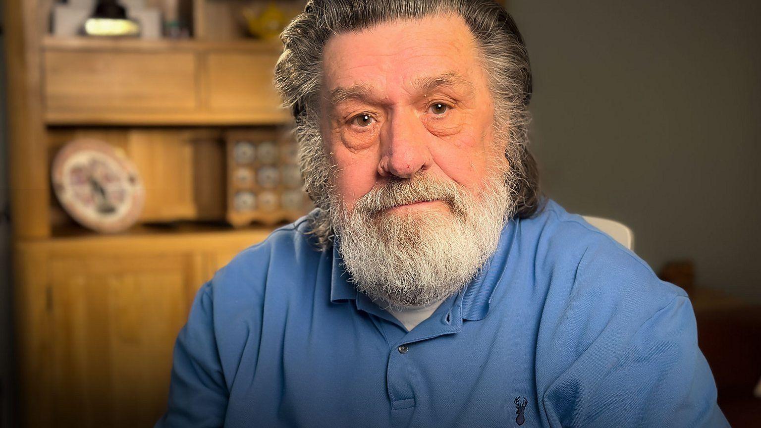 Ricky Tomlinson, in a blue shirt, staring down the camera lens.