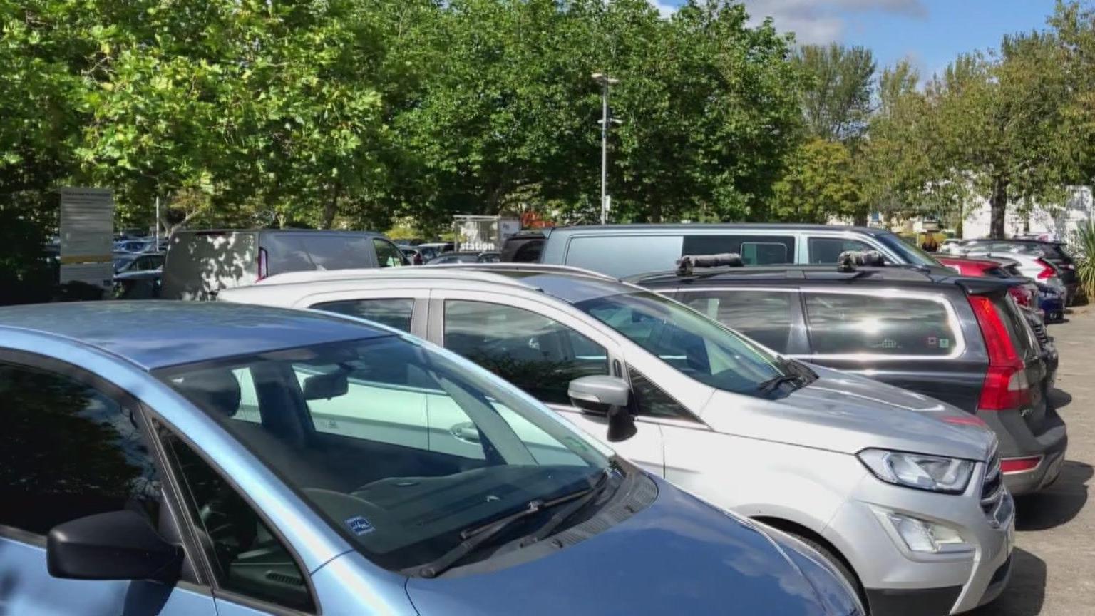 Cars parked in a car park with trees in the background 