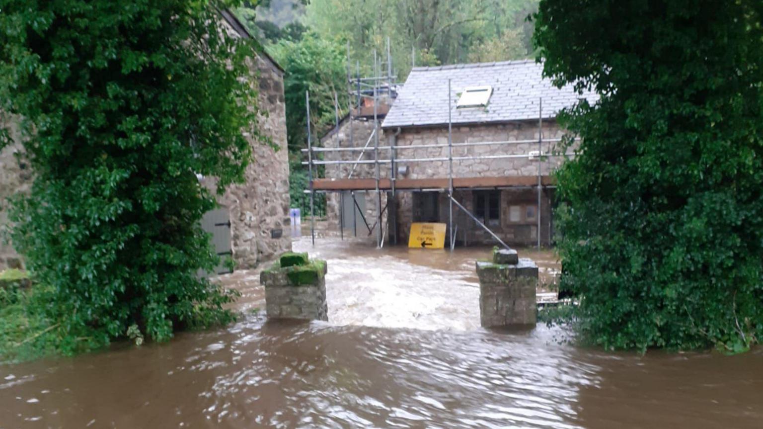 Farm house with mill in country park surrounded by flood waters