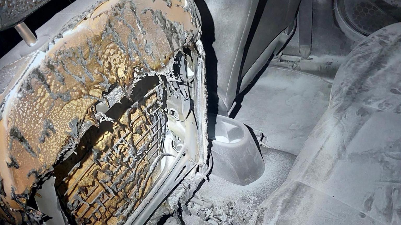 The burned our interior of the car. It's covered in ash which the back of the passenger seat has burned away leaving the metal frame.