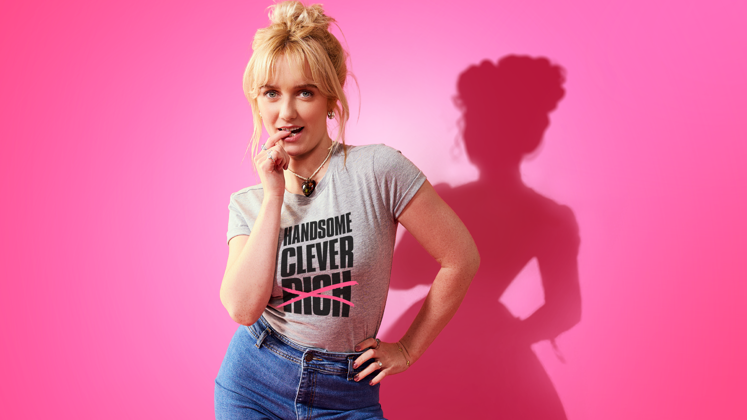 Amelia Kenworthy as Emma wearing a grey T-shirt with her blonde hair piled up in a bun.