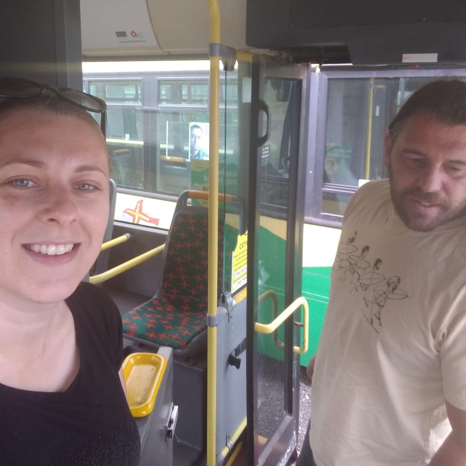 A woman and mad stand in the doorway of a bus.