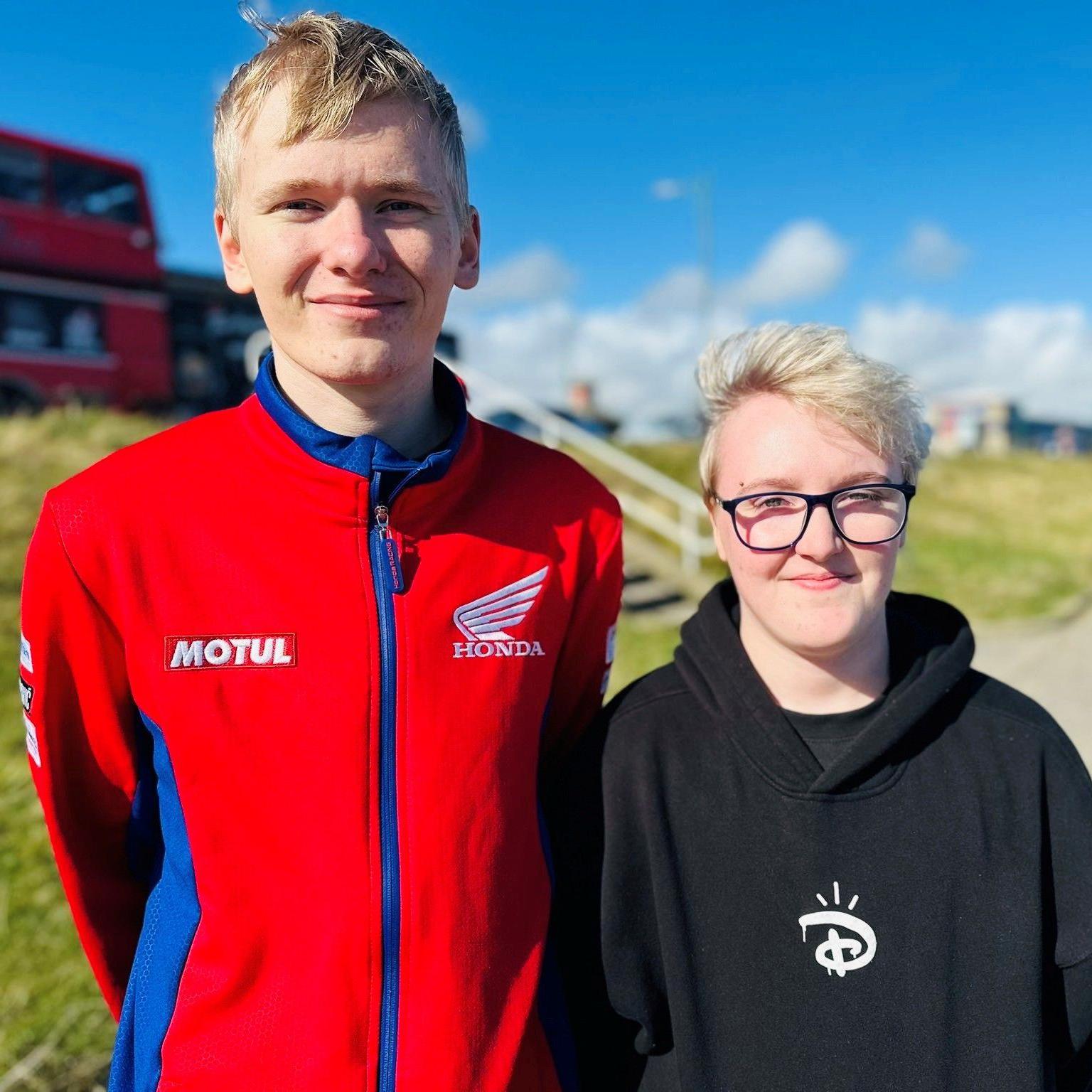 Man and woman, Kyle Simpson and Bo Cain, looking at camera at Aberdeen beach, he is wearing a red top and she is wearing a black top.