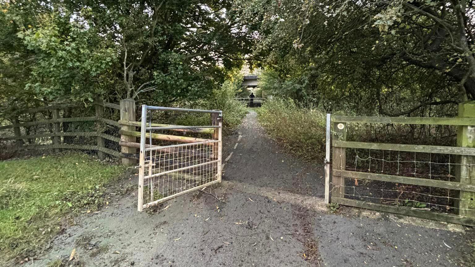 An open gate on a country lane which goes through Tewkesbury Nature Reserve. 