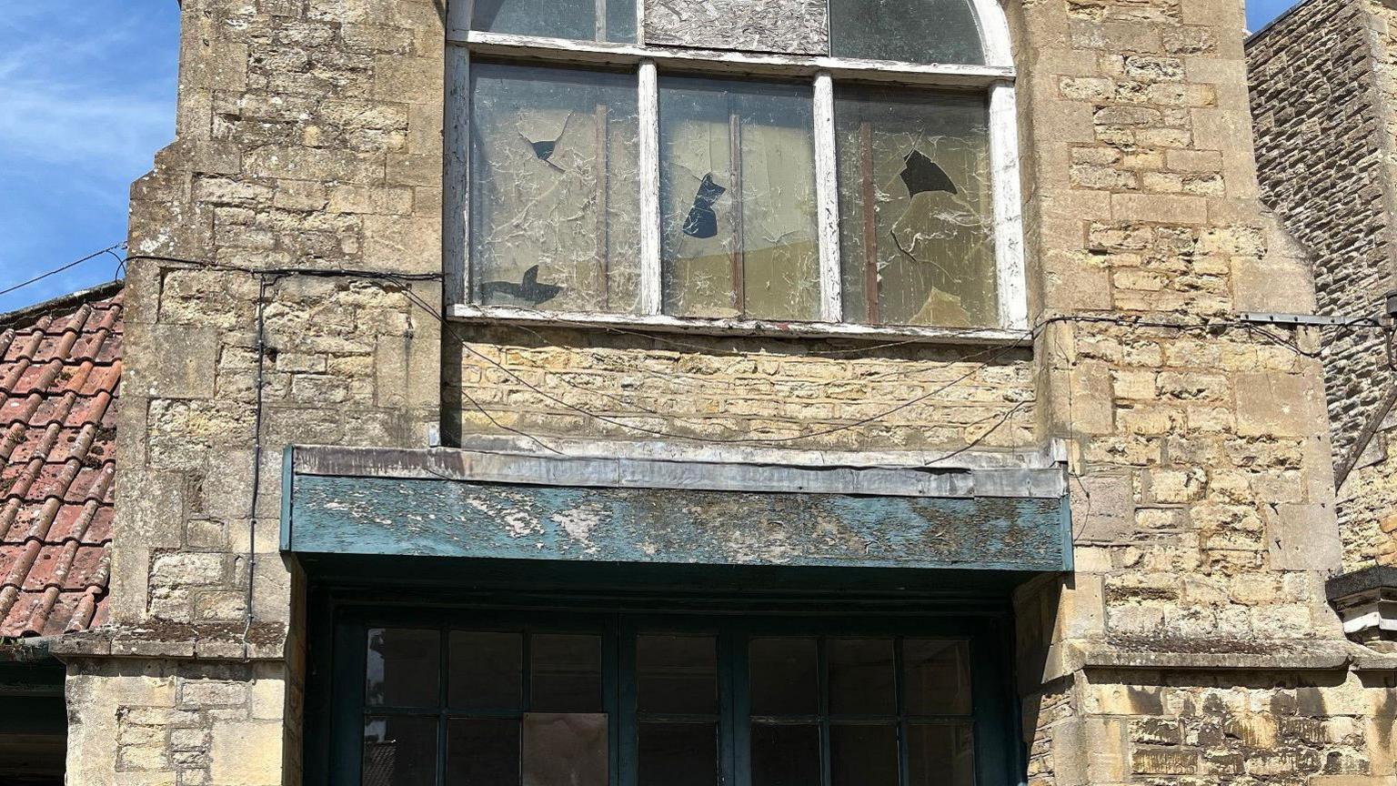 Facade of old stone building with cracked windows and in need of extensive repairs