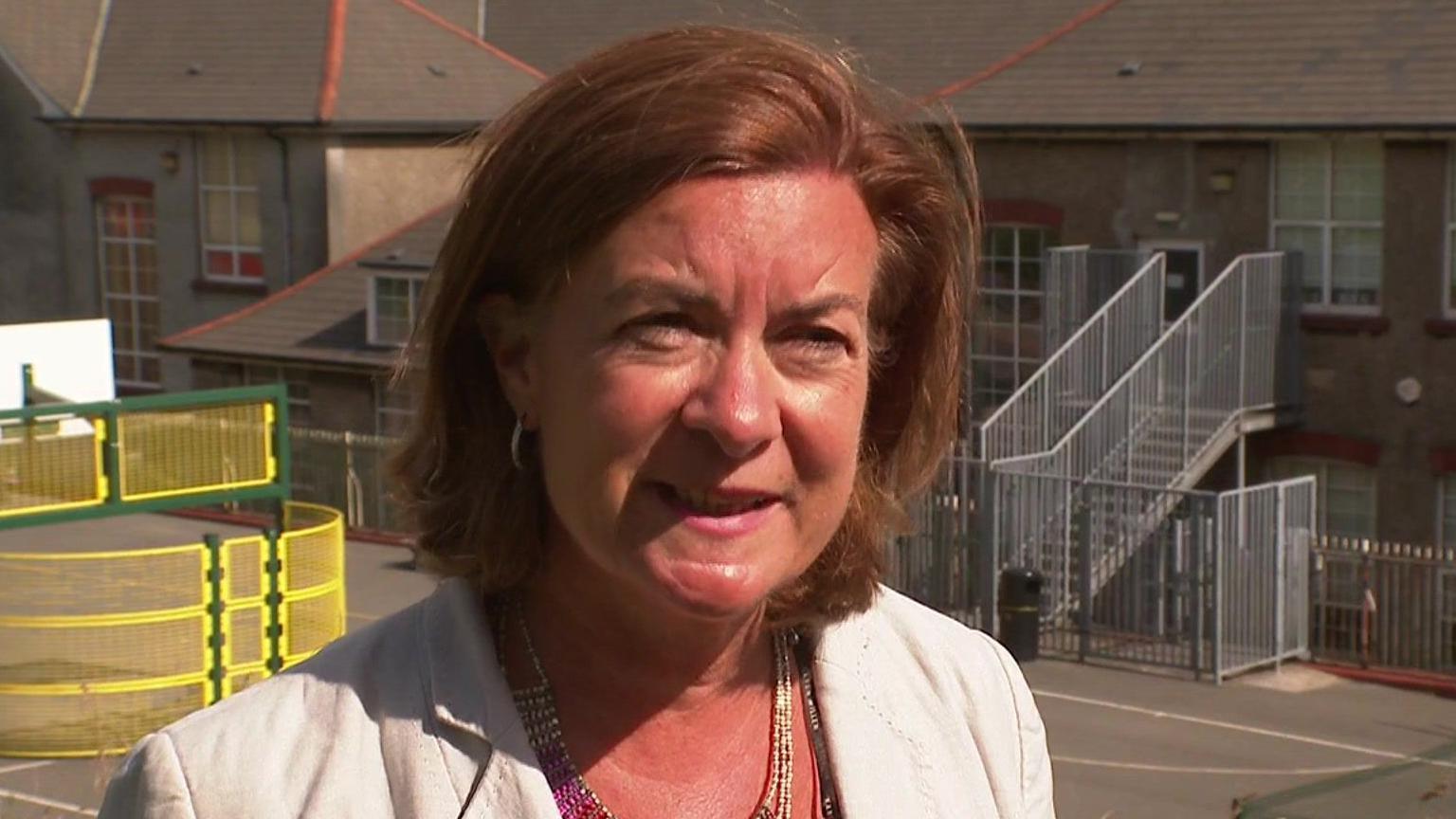 Eluned Morgan speaking in front of a school.