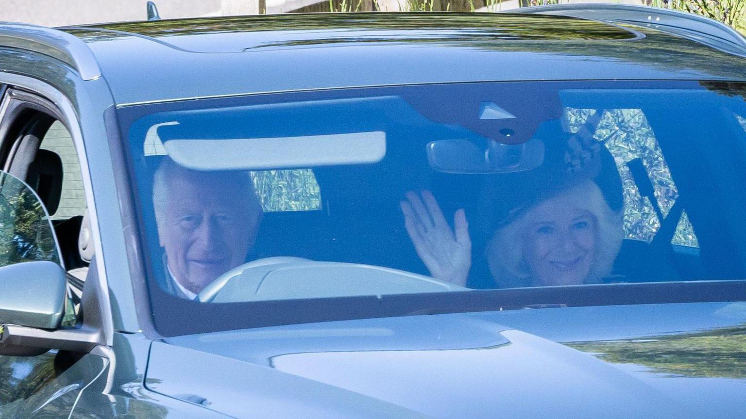 A smiling King Charles III and Queen Camilla, who is also waving her right hand, as they arrive to attend a Sunday church service at Crathie Kirk, near Balmoral.
The King is driving a dark grey Audi and the Queen is sitting in the front seat.