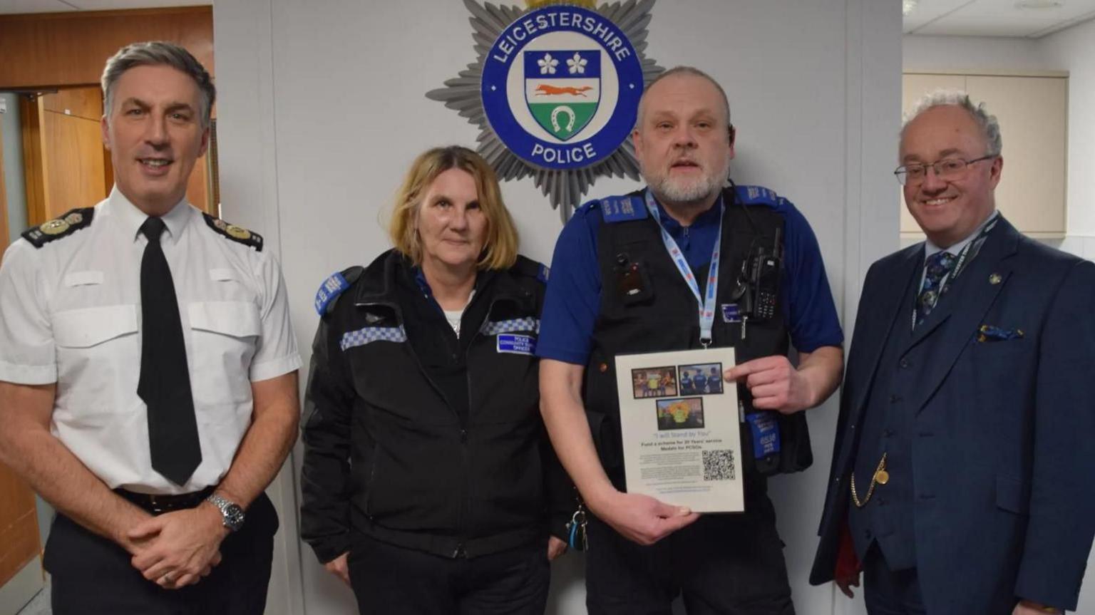 The four people stand infront of a Leicestershire Police sign at force headquarters.  Pete holds up his petition. 