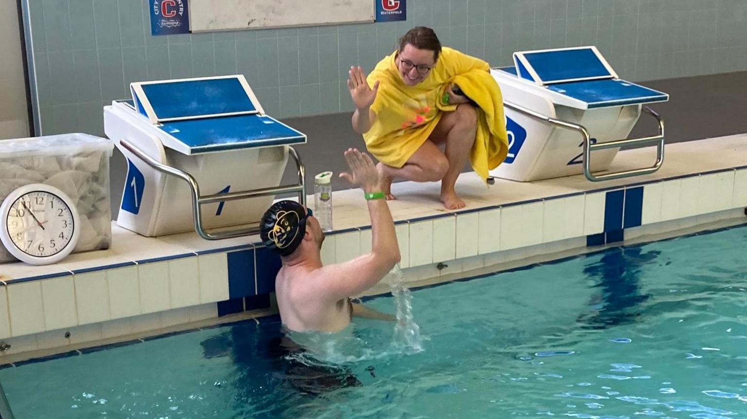 Debbie Woods next to the pool with her right arm visible and a man in the water.