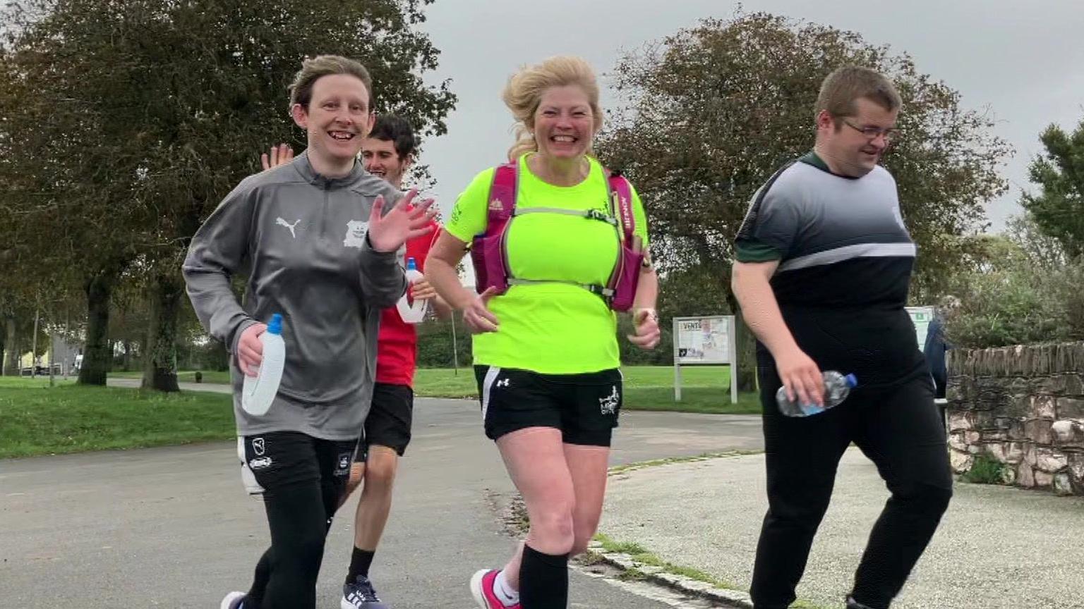 A group of four runners wearing sports attire while out for a jog in a park in Plymouth.