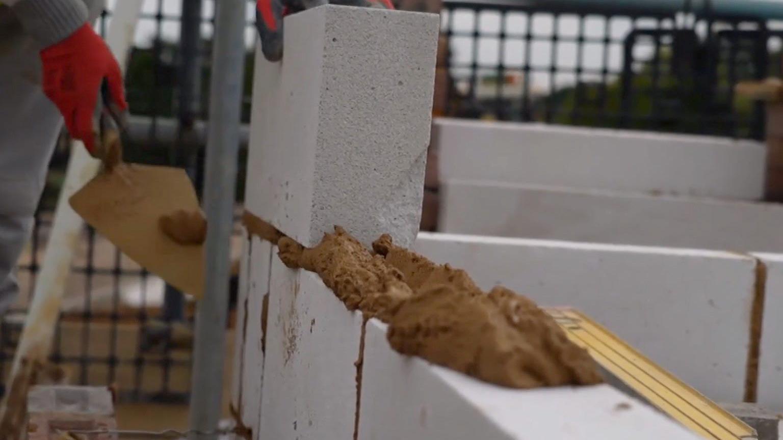 Bricks being laid with a trowel smoothing the cement inbetween the blocks. 