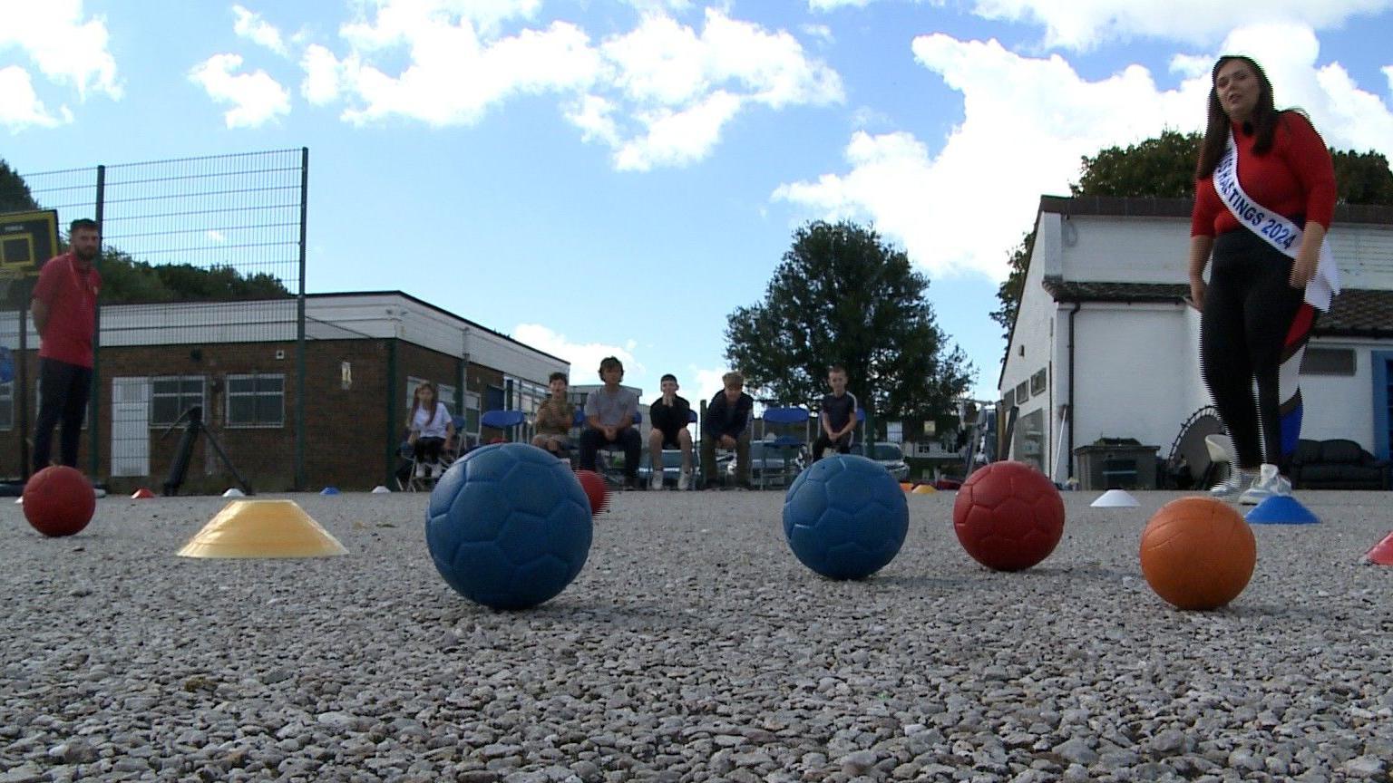 Coloured footballs lie on the ground.