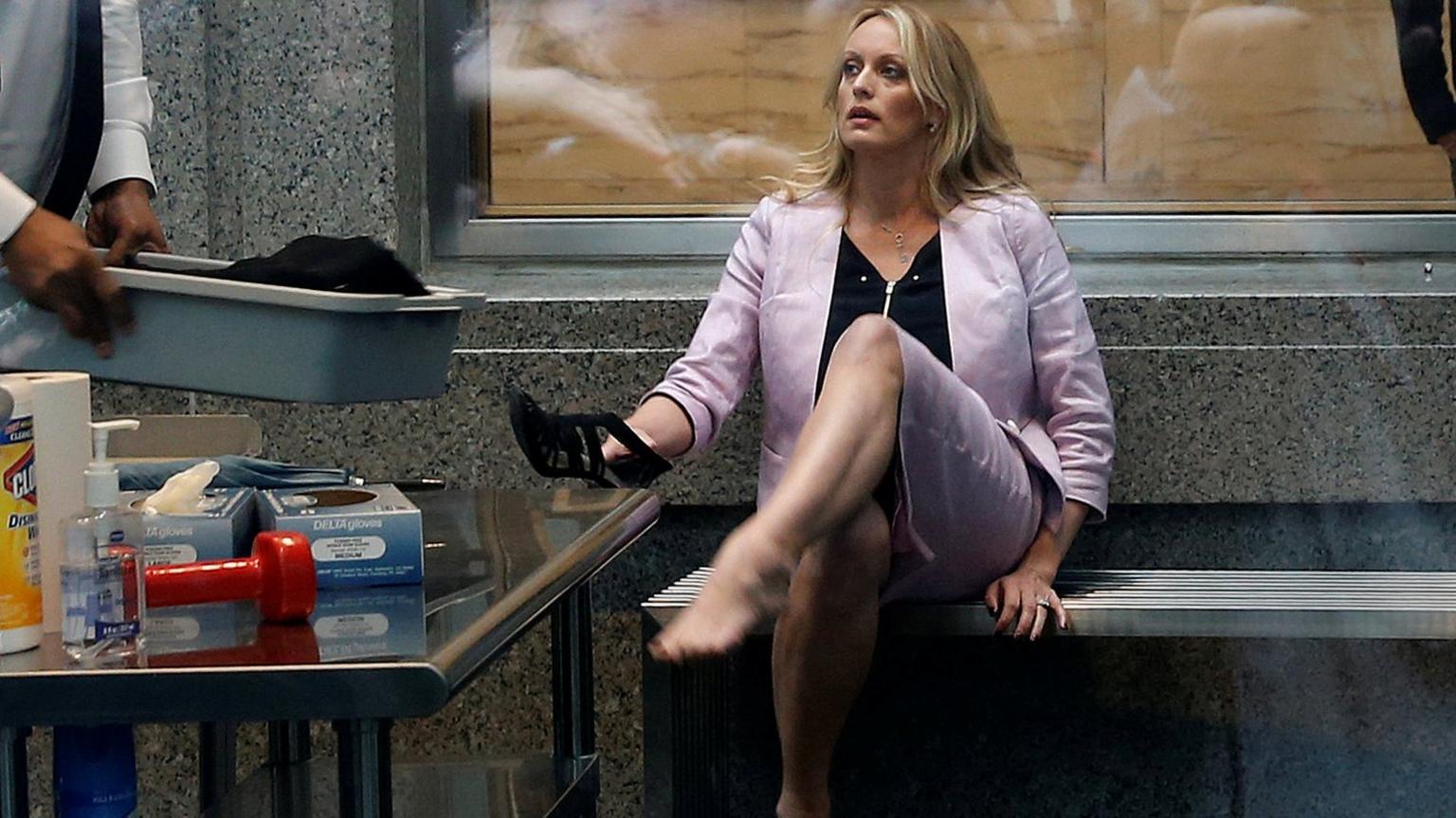 Adult-film actress Stephanie Clifford, also known as Stormy Daniels, puts her shoe back on after passing though a security screening