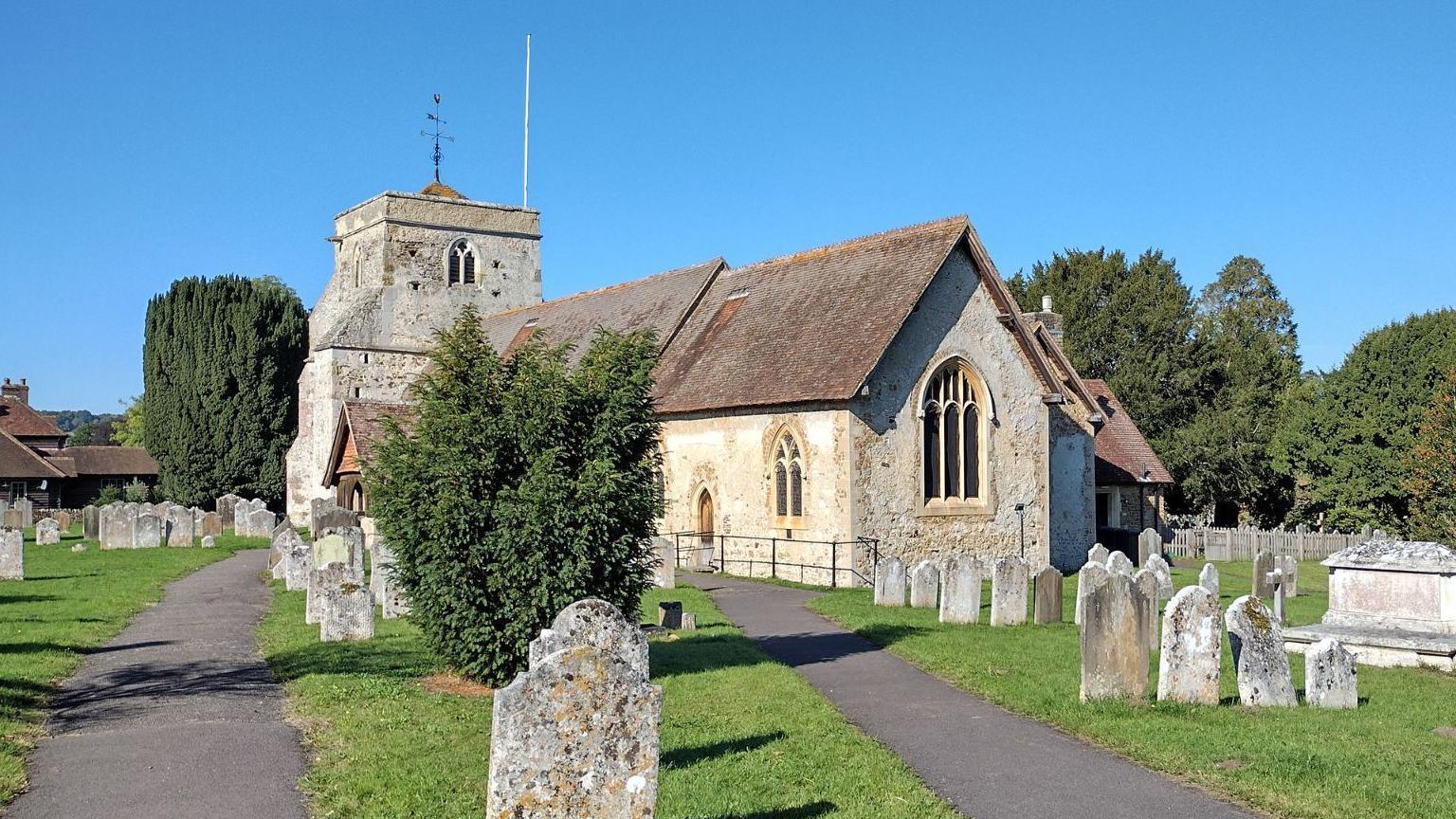 A small grey church in a graveyard on a sunny day