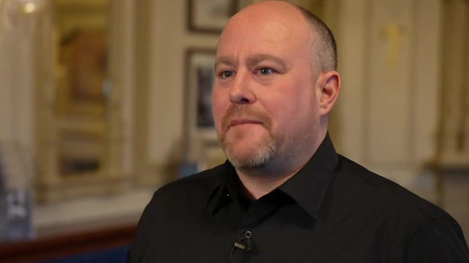 Adam Knight with shaved head, goatee beard, black shirt in the Grand Theatre bar