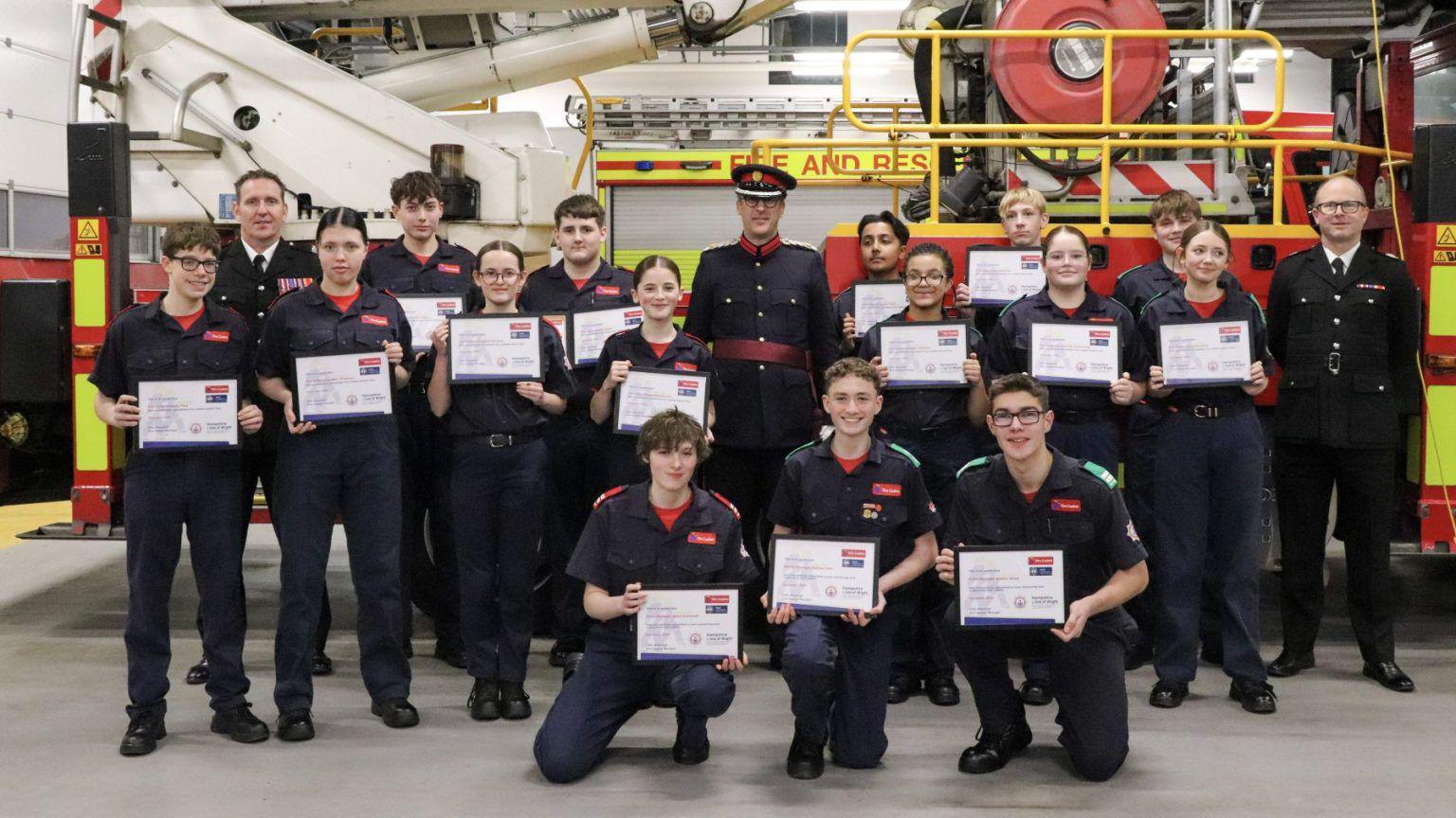 A group of fire cadets photographed in front of a fire engine.