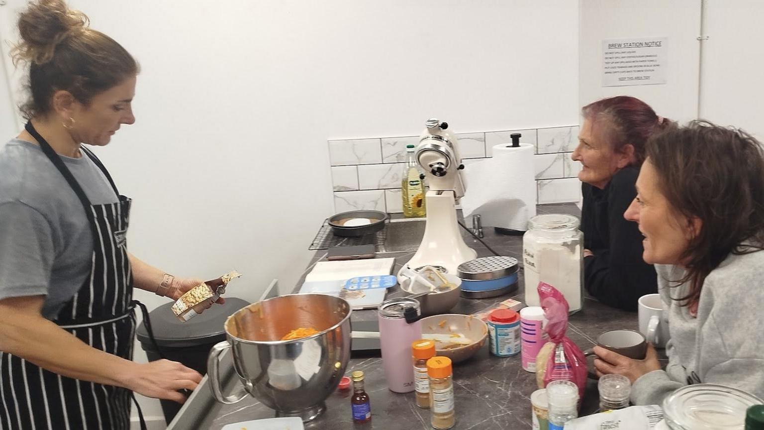 Students observe a volunteer cook at work.