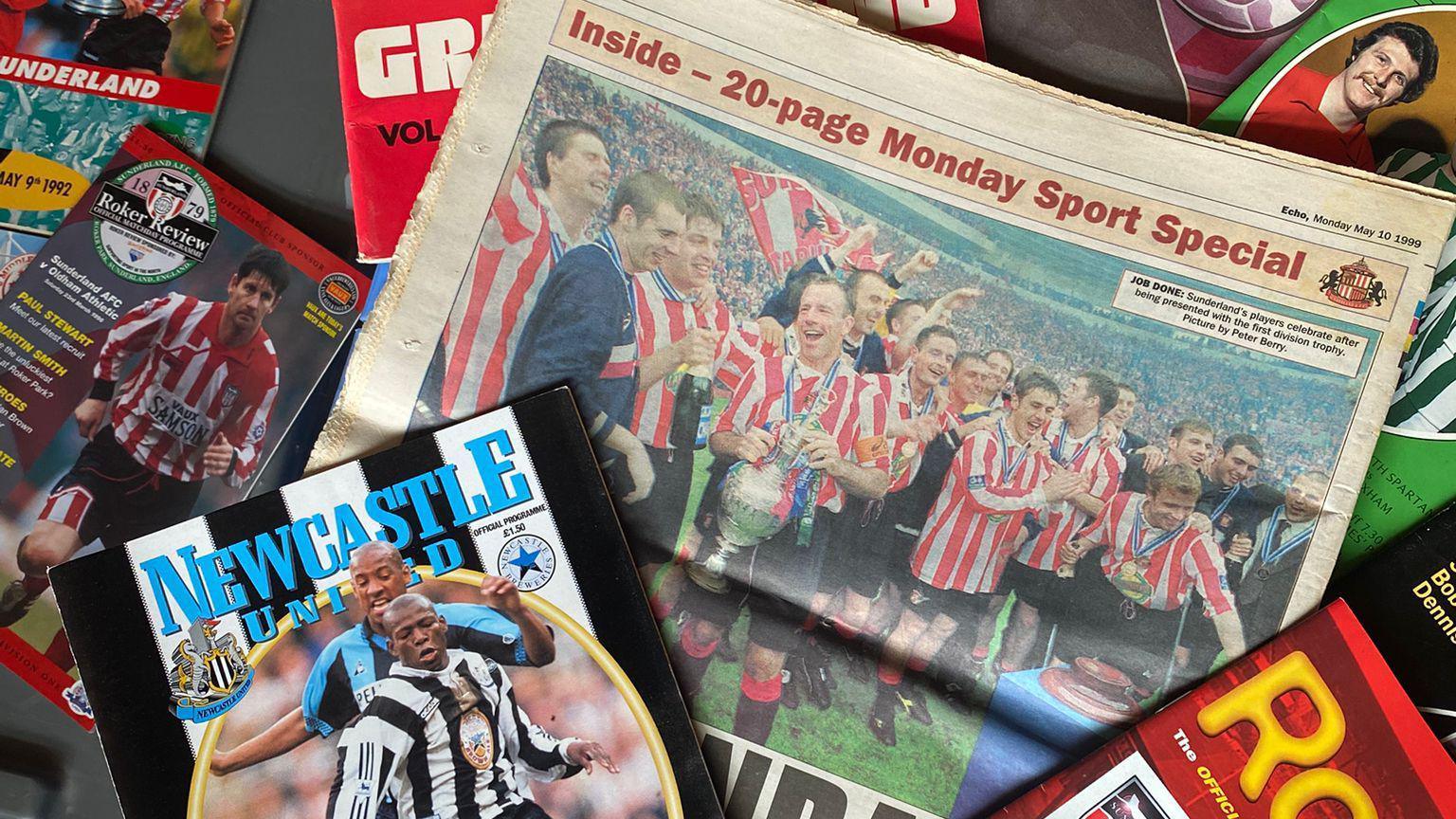A collection of old magazines and newspapers, mostly with Sunderland players on the front in red and white shirts. There is a Newcastle United programme in the left corner.