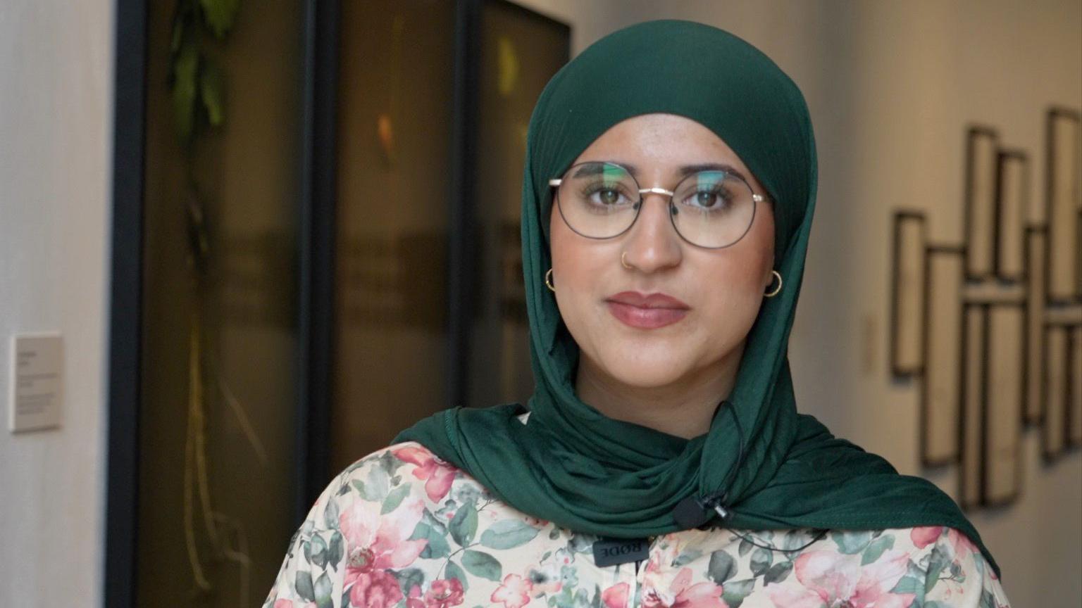A young woman of Pakistani heritage stares at the camera