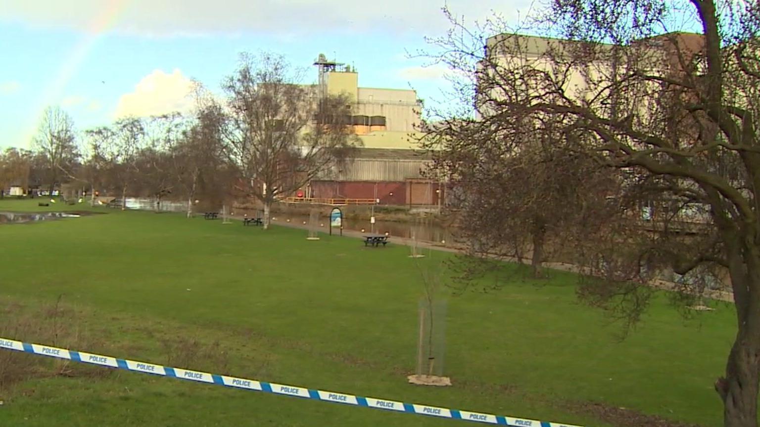 A line of police tape barring entrance to an embankment. The canal can be seen in the distance. 