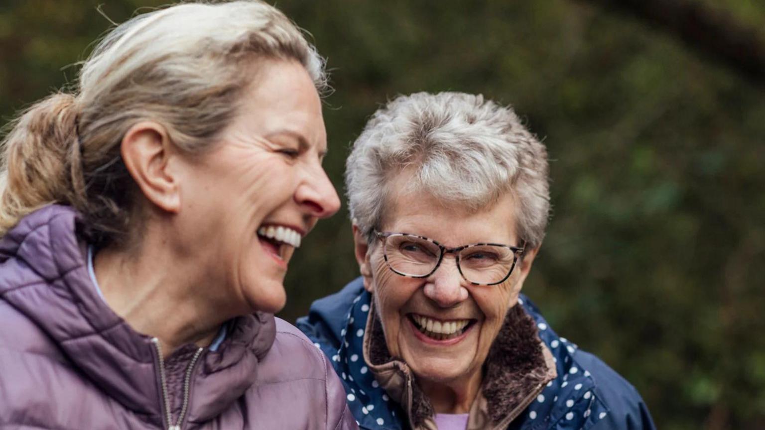 Two women walking laughing along with one another