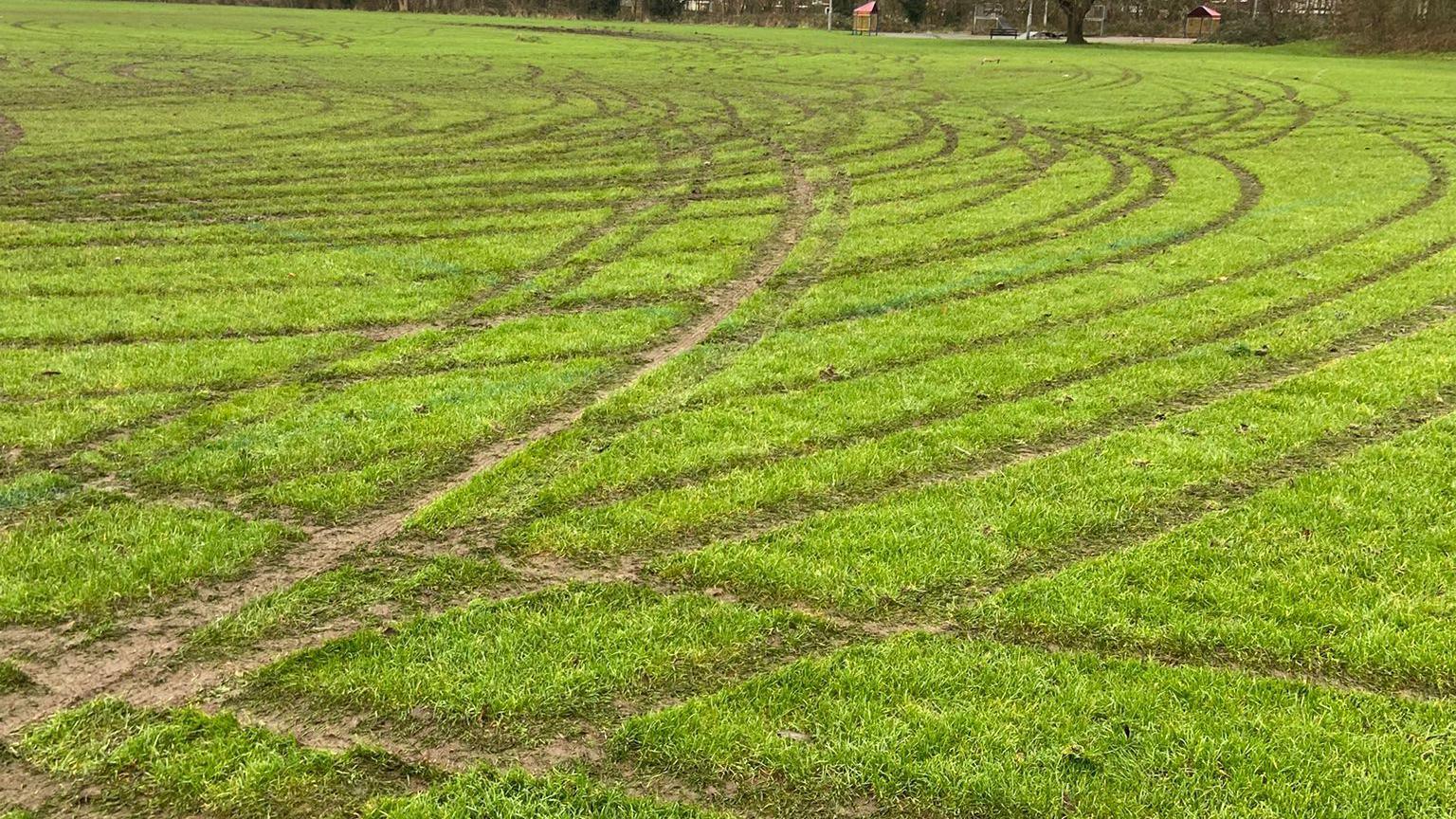 A football pitch with deep quad bike markings across the grass