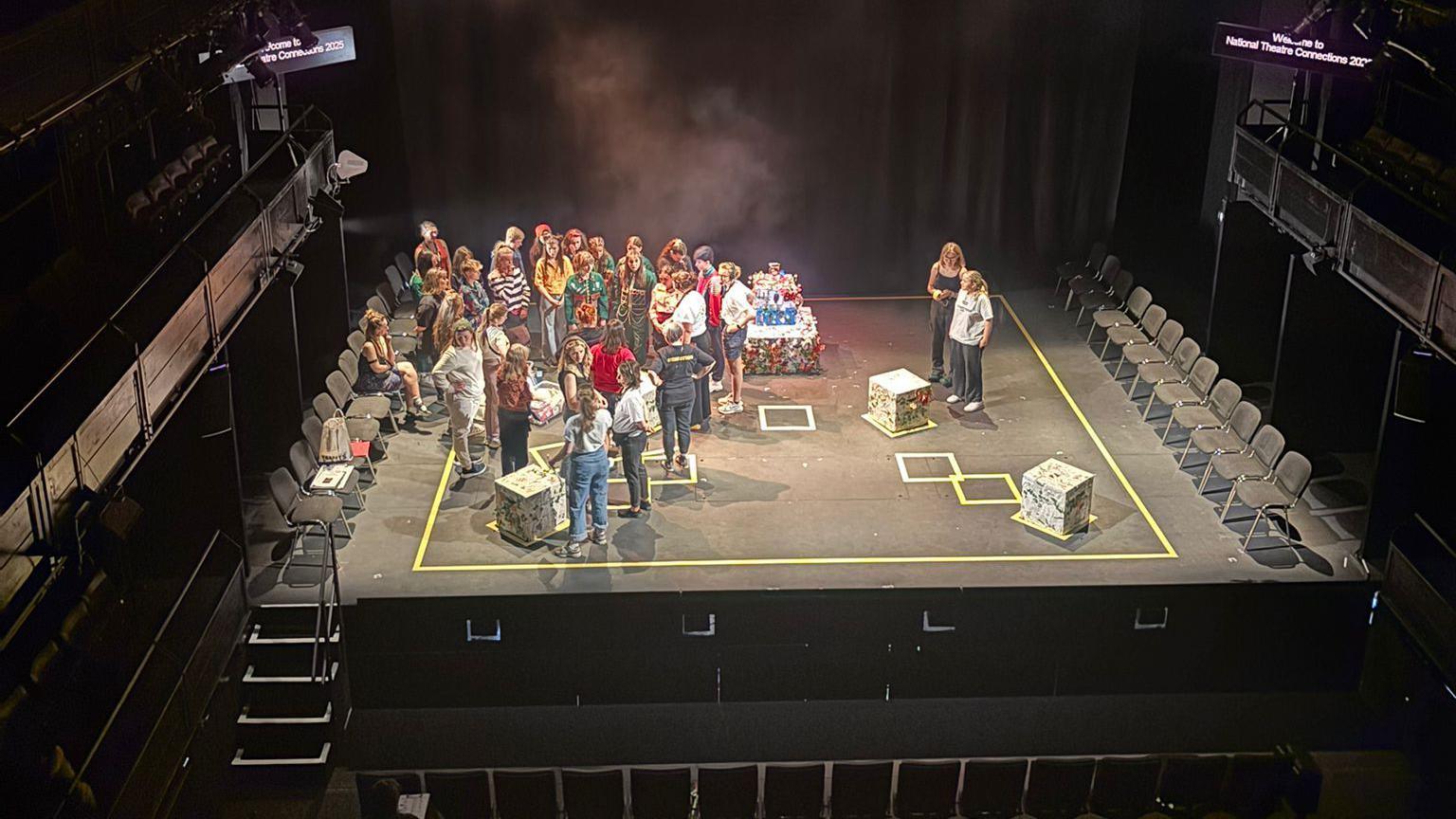 An aerial shot of the stage. The group is standing to the left and the stage is marked out with yellow tape. 