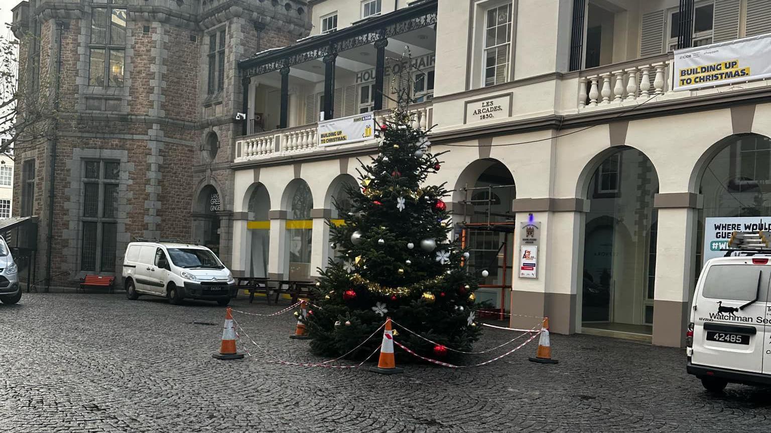 Photo shows the Christmas tree on the floor with orange cones and tape surrounding it.