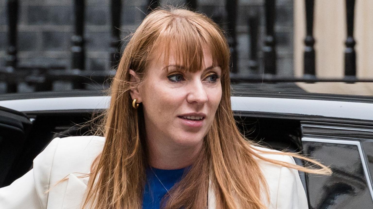 A head and shoulders crop of an image of Angela Rayner looking away from camera as she's getting out of a car in front of the railings of Downing Street in September