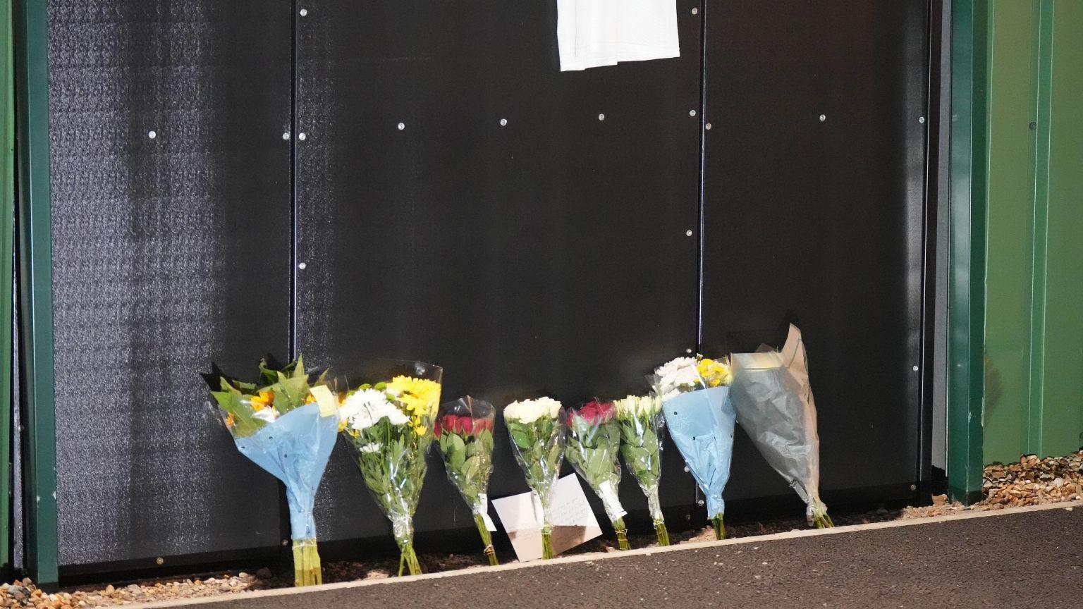 Seven bunches of flowers leaning against a black wall