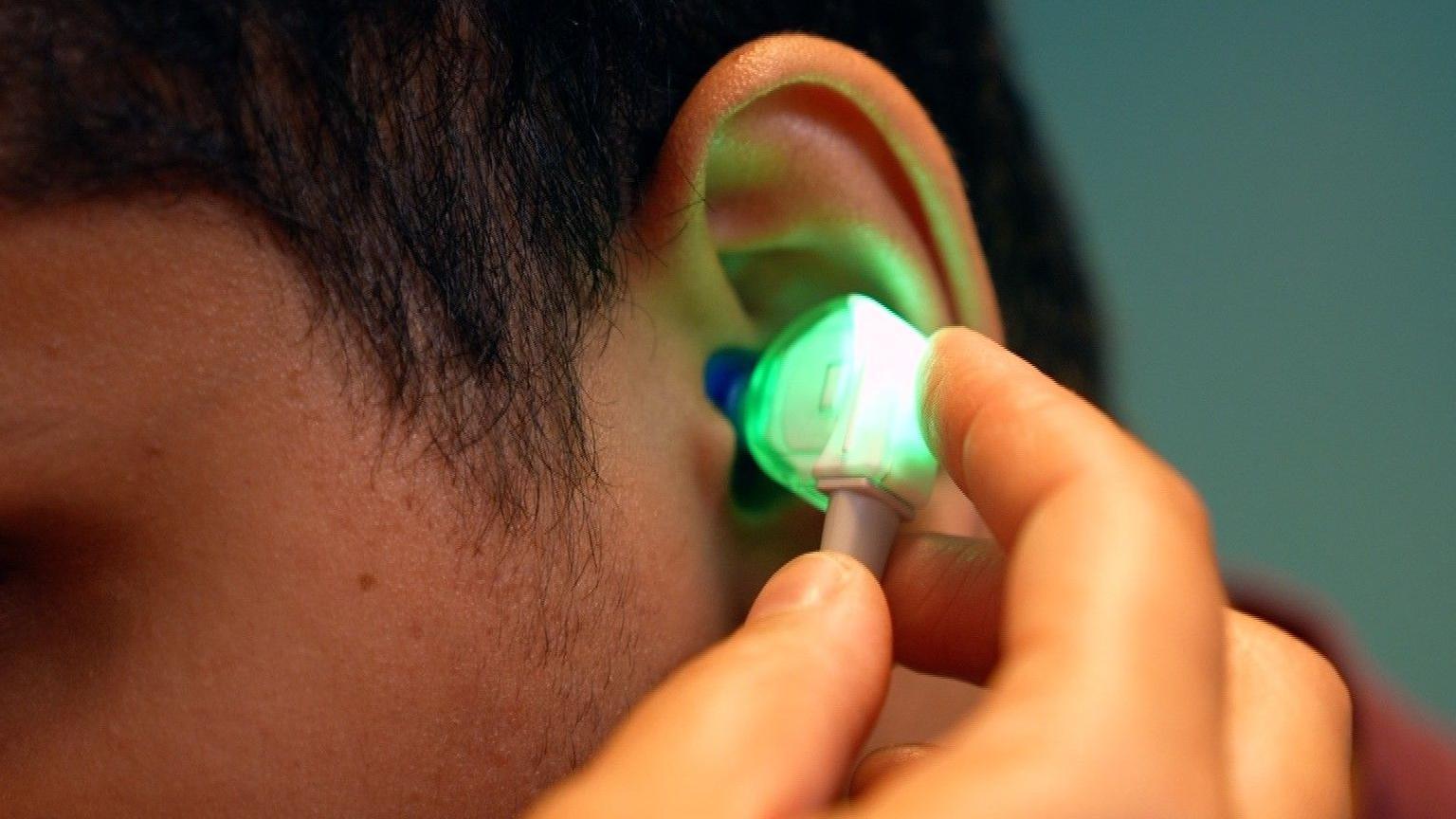 A device is put in a student's ear to check hearing