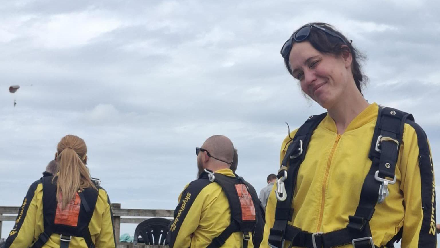 Belinda wearing a yellow safety gear suit smiling with sunglasses on her head.