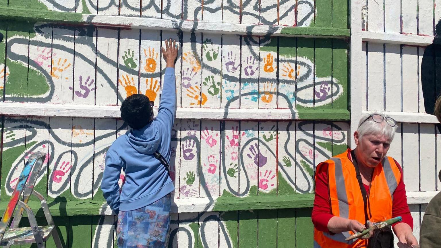 Someone makes a hand print on the mural