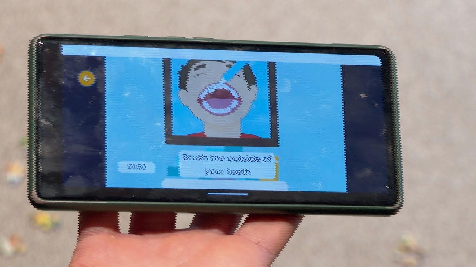 A phone with a screen showing a cartoon boy with some words about brushing teeth.