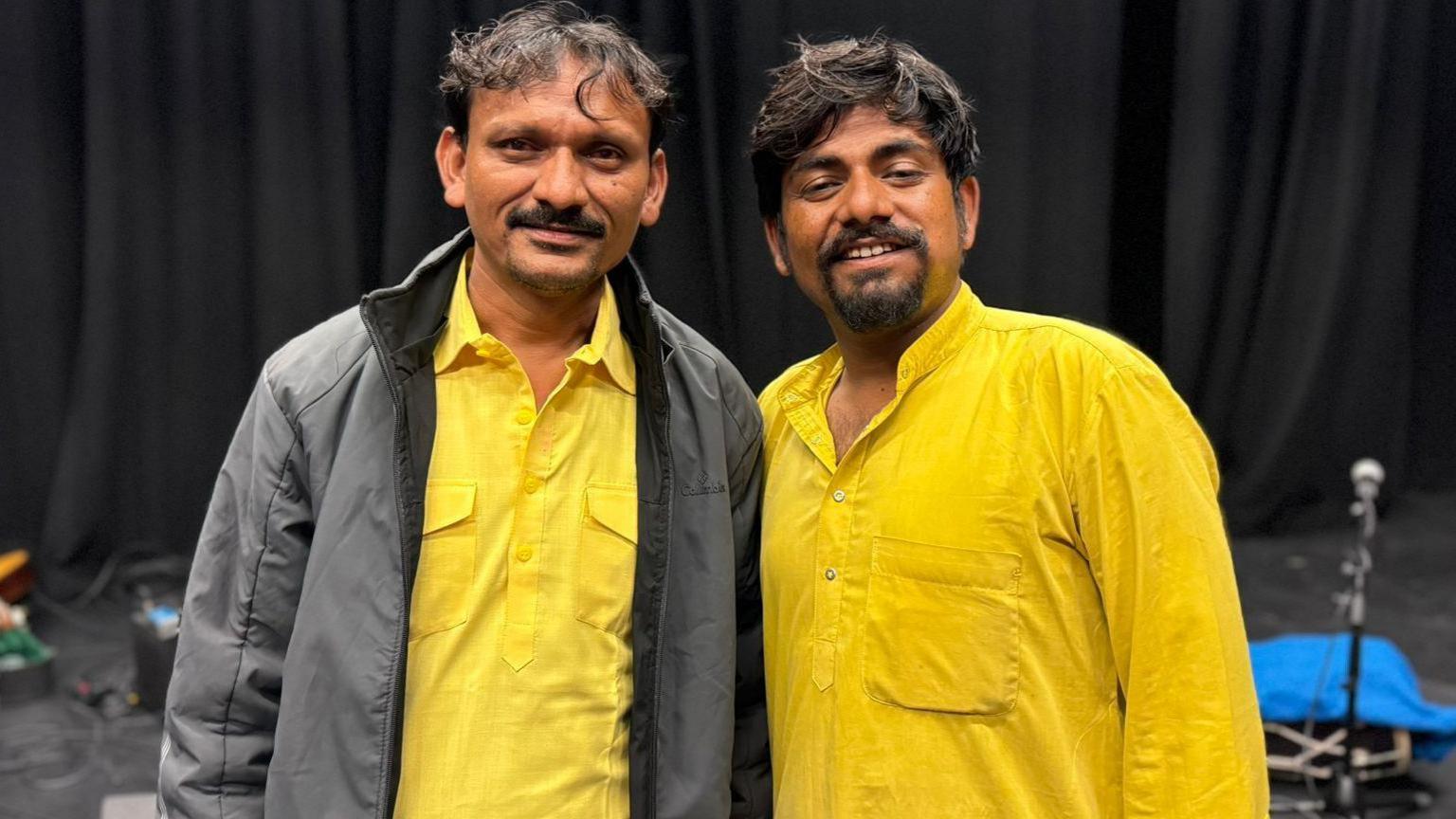 Asin and Sawai smiling. Both are wearing yellow clothes. Asin is wearing a grey jacket. They both have brown hair.