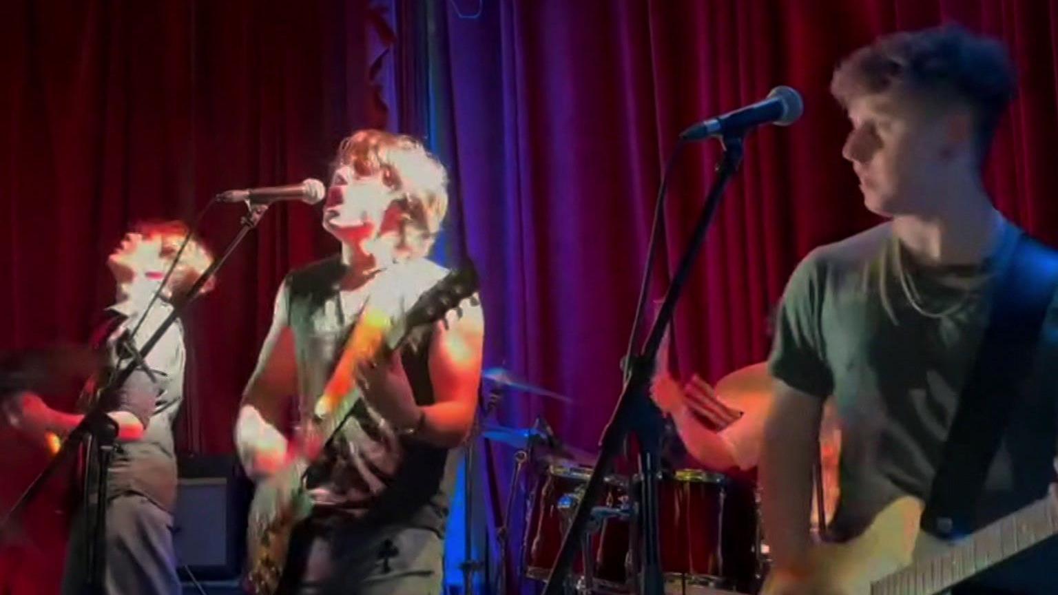 Three band members playing guitars and singing.