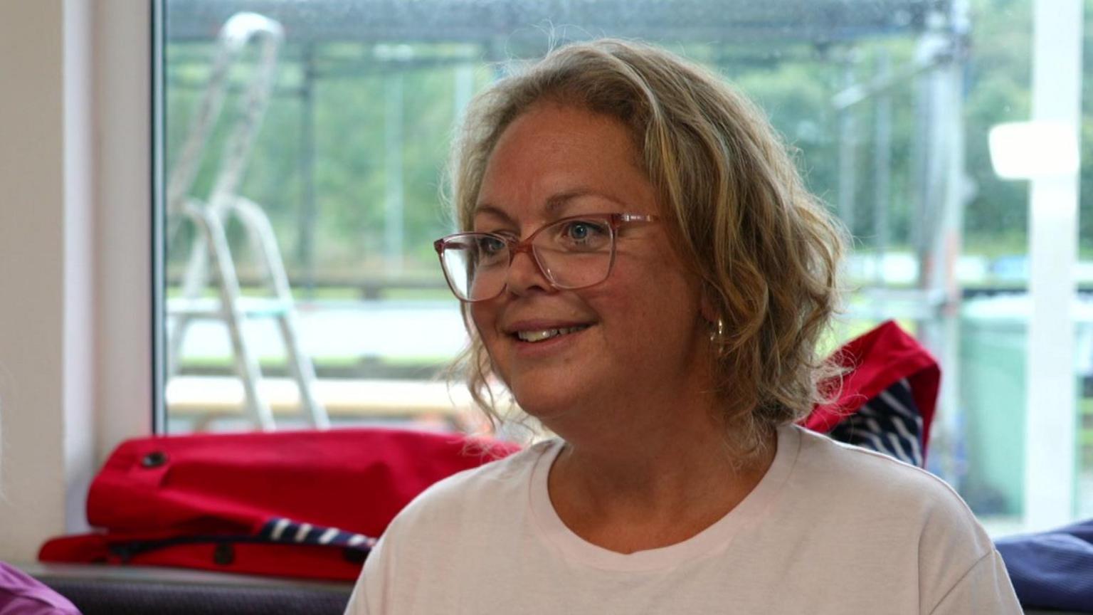 Chevi Mcilroy wearing glasses and a white T-Shirt, smiling