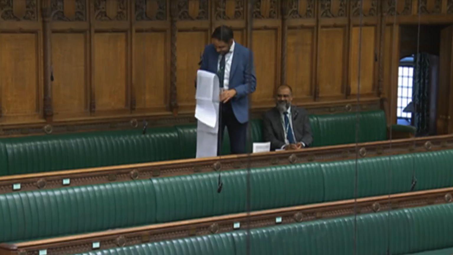 Shockat Adam MP unfurls a long speech, stretching over several pieces of paper, for comic effect