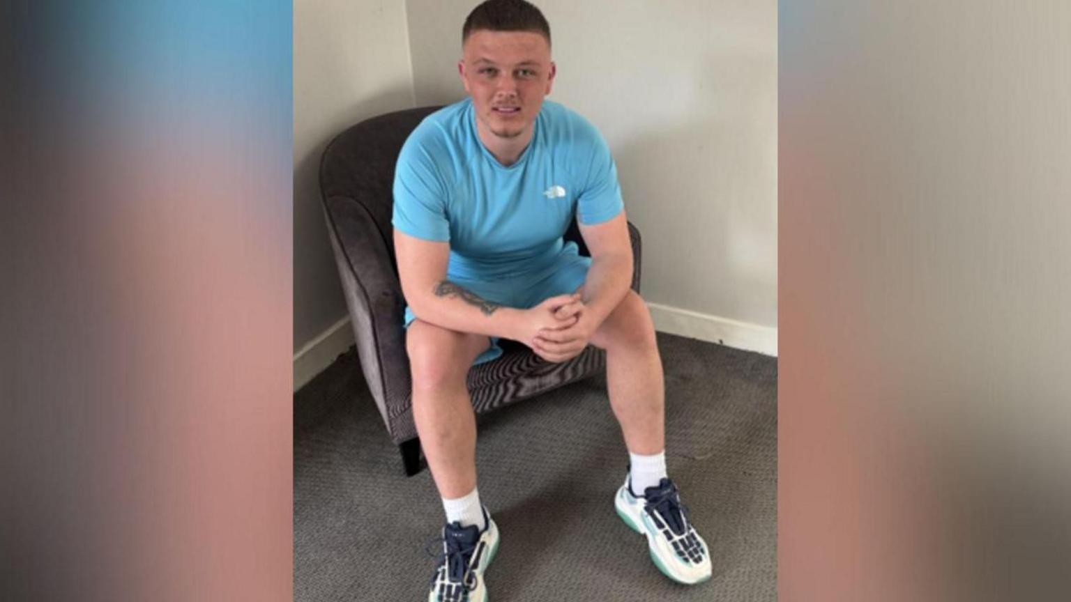 Image of Dale Martin. He is sat on a chair and is wearing a sky blue t-shirt and shorts.