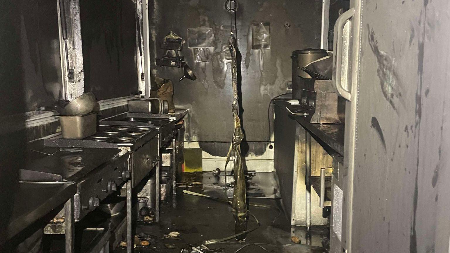 Inside a van kitchen, soiled with ash and melted walls. 