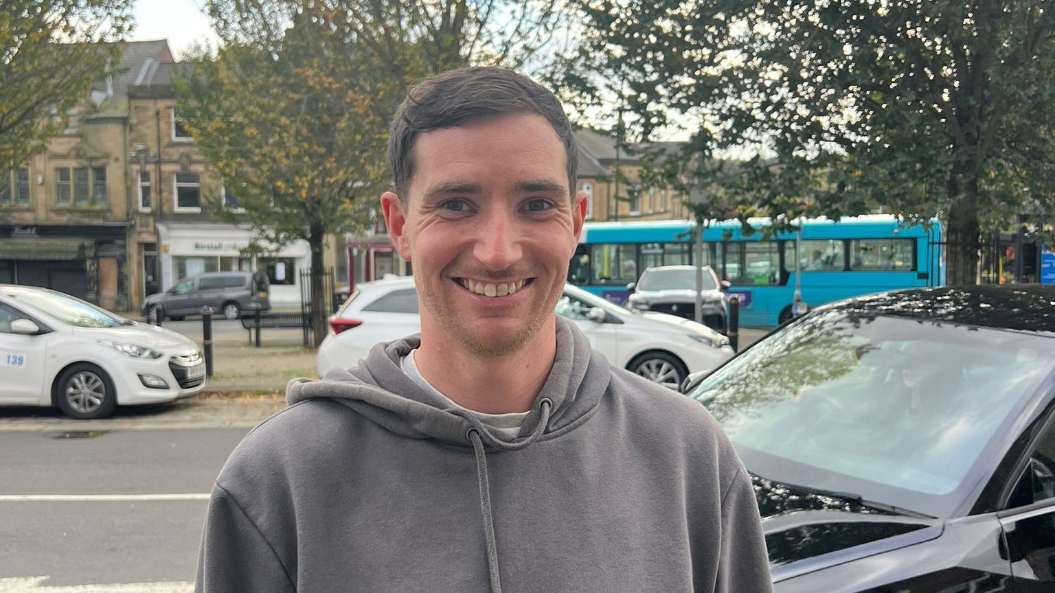 Alex Miller, who wears a grey hoodie, seen smiling in the street in Birstall.