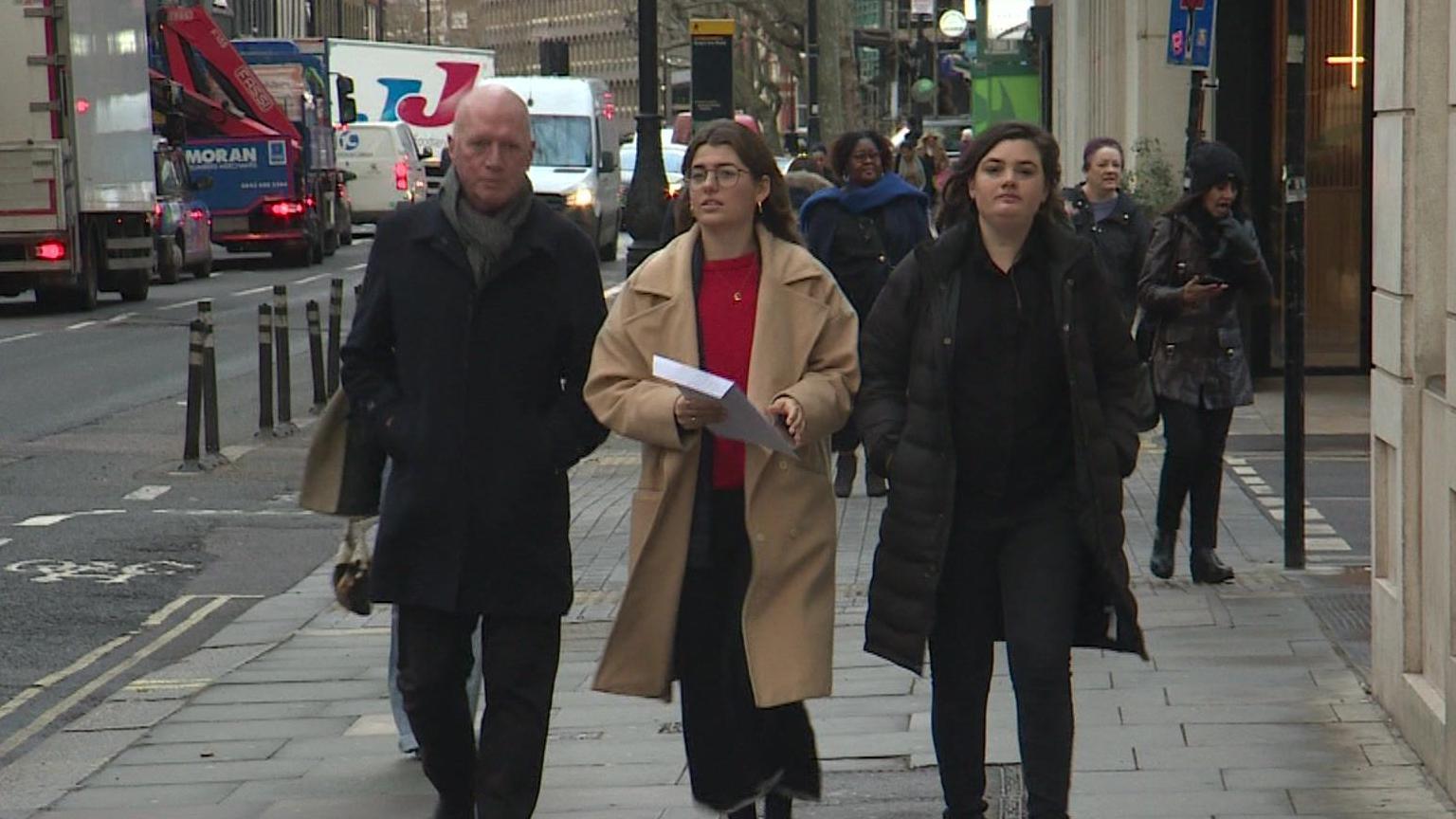 Matt Wrack, an unidentified team member and Bekah Sparrow walk side by side on the street towards the regulator's building, carrying the letter of complaint in a white envelope