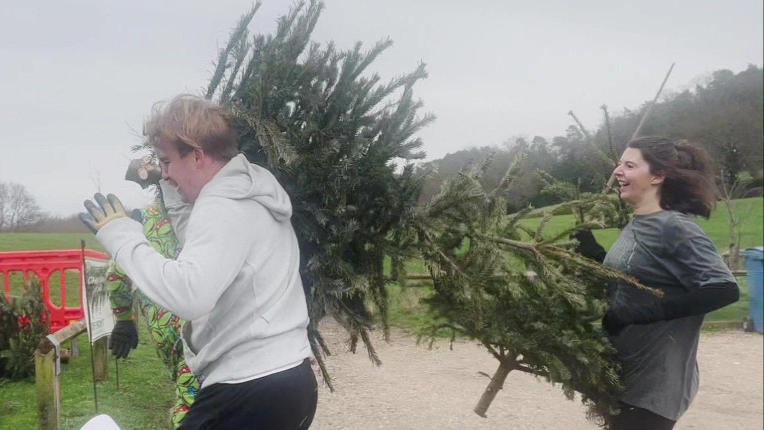 Two villagers run towards the finish line with their Christmas trees.
