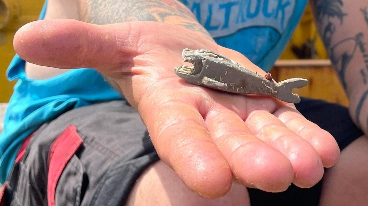 Richard West's open hand in which lies the sea-worn grey Lego shark