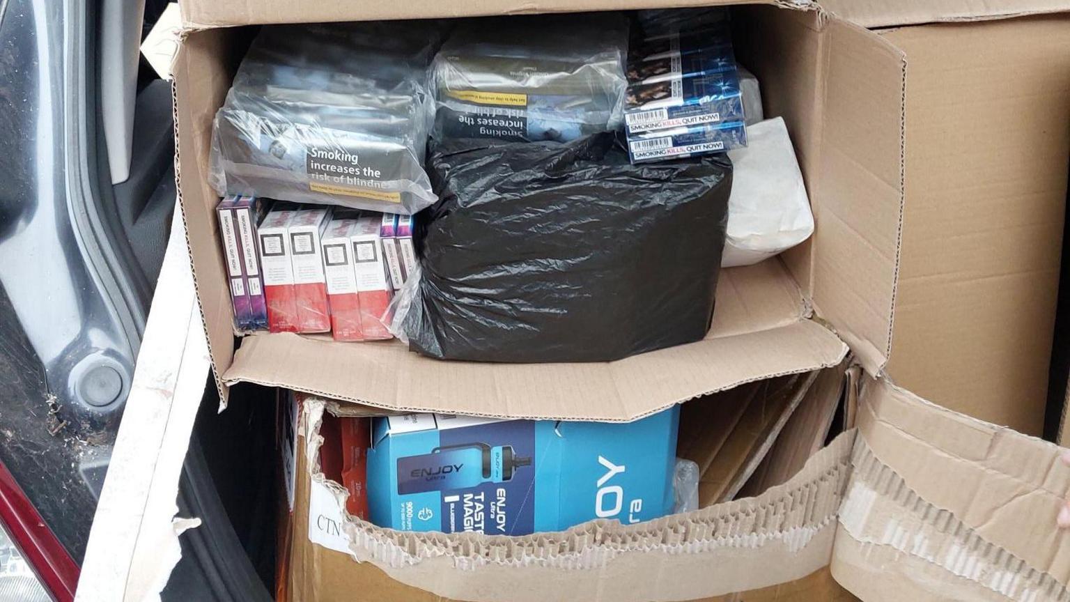 Two boxes of items in the back of a vehicle. The boxes are open, items are in bags, and the doors are open.