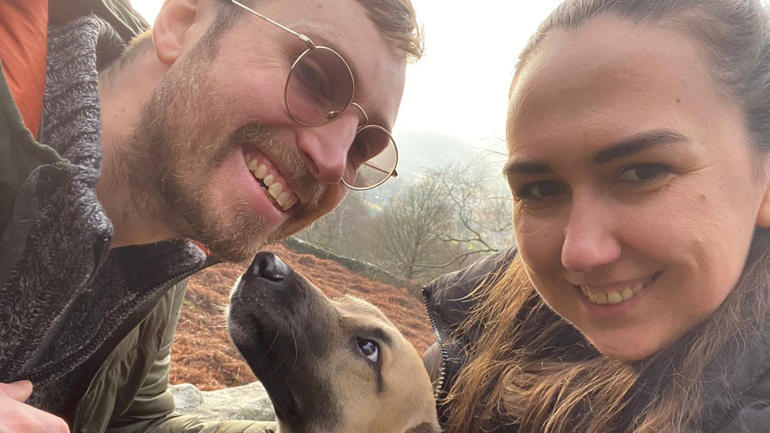 A dog between a smiling man and woman