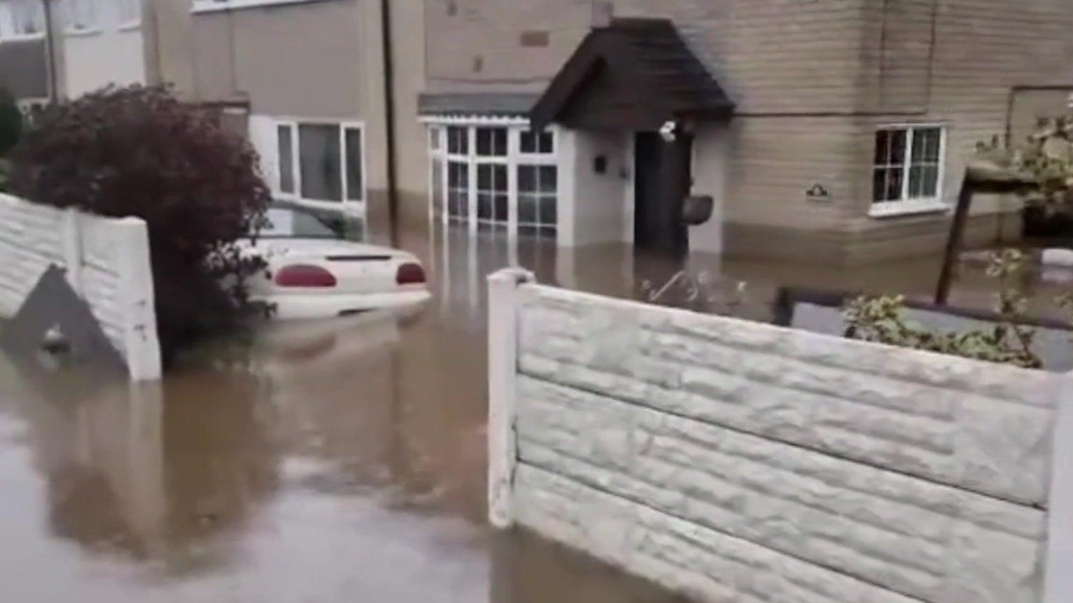 A front drive with flood water covering the wheels of a white car