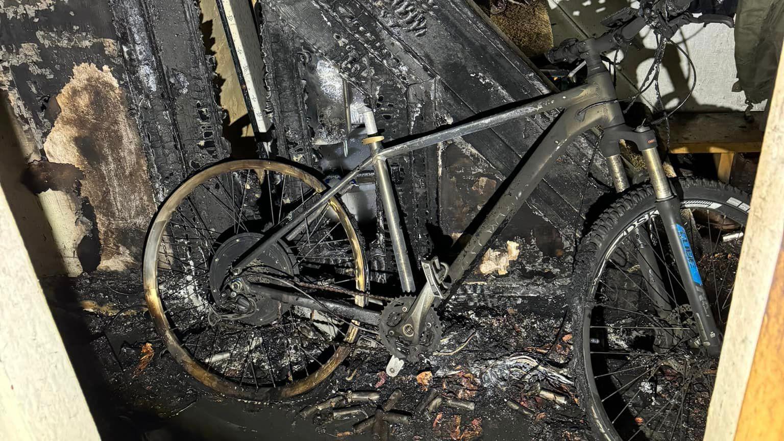 A burned-up electric bike in the hallway of a house.