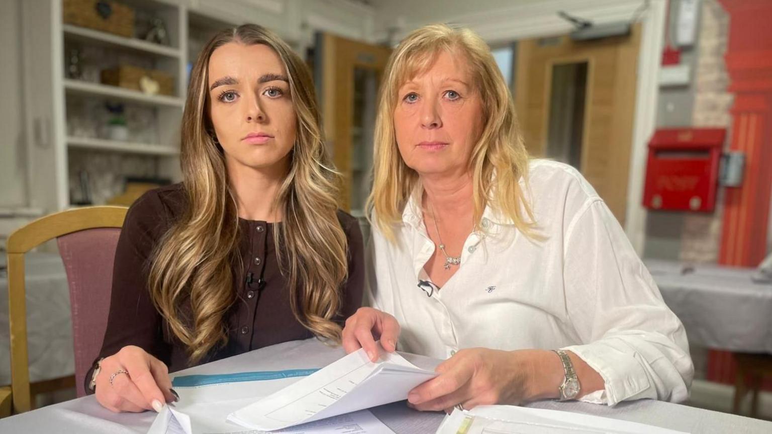 Claire Doxey and daughter Kelly-Jay Beeson look directly at the camera with their 4com contract in front of them on the table.